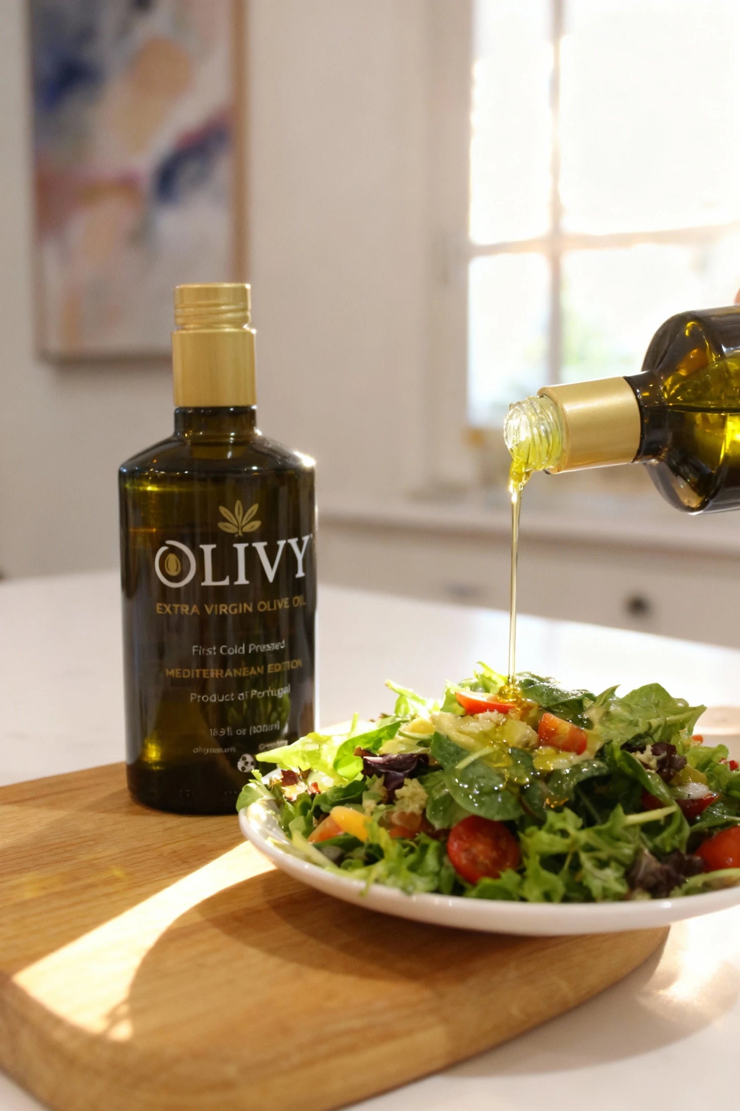 Olivy olive oil bottle being poured over a salad on a wooden cutting board.