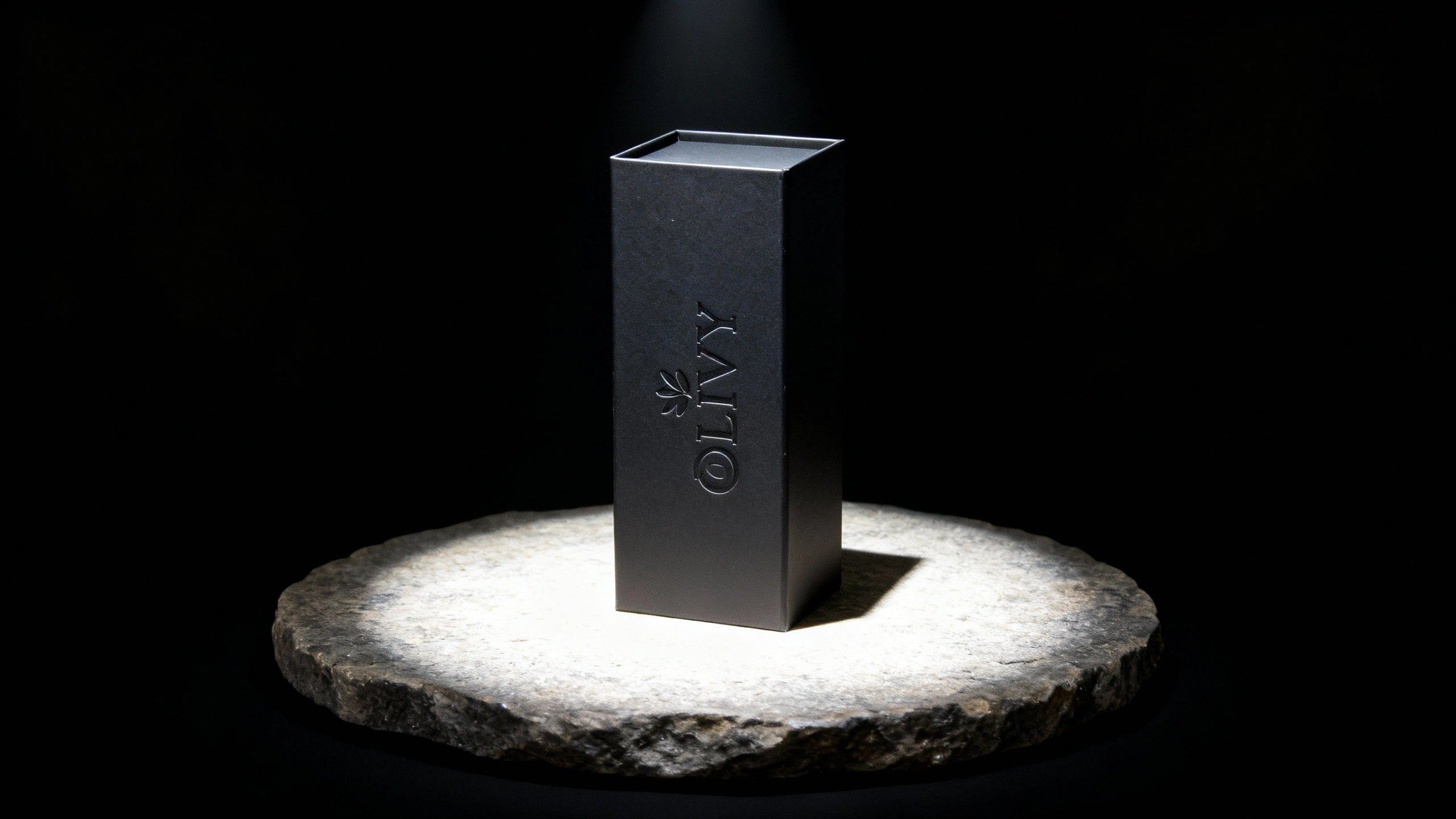 Black rectangular box with 'OLIVY' branding on a stone platform against a black background