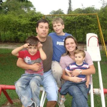 Family of five with three children on a swing set in a park.